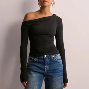 Svart oneshoulder långärmad topp - Svart långärmad topp med oneshoulder-design. Toppen är använd vid ett tillfälle så den är i ny skick. 