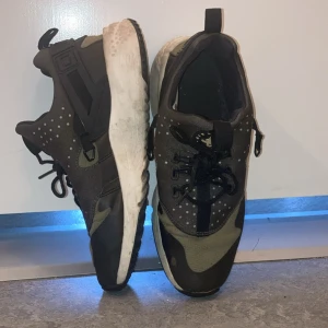 Nike Air camouflage skor - Nike sneakers i svart och olivgrönt med camouflagemönster och vita prickar. Skorna har snörning, vit sula och rund tå. Ovandelen är i syntetmaterial och textil, perfekt för dig som gillar streetstyle och sportig look.