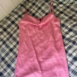Rosa satin klänning från Vero Moda - Snygg rosa kortklänning från Vero Moda i satinliknande material. Klänningen har tunna axelband och en snygg draperad urringning. Aldrig använd 