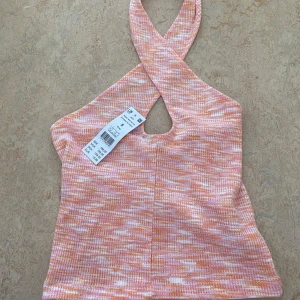 Fest topp - Orginalpris 199kr. Superfin  halterneck topp från gina tricot i mixade toner av rosa, orange och vitt. Toppen har korsade axelband och är ärmlös med en snygg, lite croppad passform. Aldrig använd, prislappen är kvar!💕