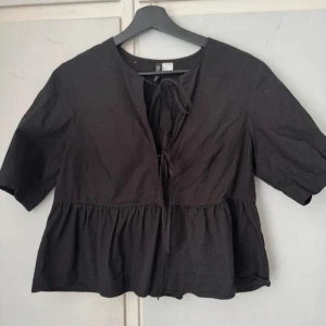 Svart blus med knyt och volang - Säljer denna fina blusen från h&m då den tyvärr inte kommer till användning längre😩Den är endast använd 2 gånger och är normal i storleken💗