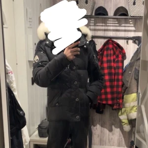 Svart dunjacka Moose Knuckles - Säljer en svart dunjacka från Moose Knuckles (äkta) med vit pälskrage och ikonisk logga på ärmen. Finns flera dragkedjor, knappar. Perfekt som vinter/ vår jacka. Ny pris :- 12000. 6000kr snabb affär men går även att diskutera!