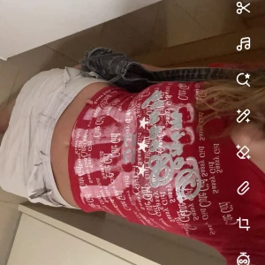 Röd v-ringad topp Miss Sixty - Röd v-ringad topp från Miss Sixty med tryck i vitt och silver. T-shirten har korta ärmar och är figurnära i modellen. Perfekt för dig som gillar Y2K-stil, 90s och statement-plagg.