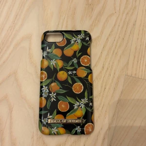 Svart med apelsiner mobilskal Ideal of Sweden - Snyggt svart mobilskal från Ideal of Sweden med färgglada apelsiner, gröna blad och vita blommor. Skalet har en glansig finish och guldig logga längst ner. Till iPhone 6