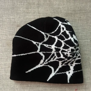 y2k mössa  - Cool svart mössa med vitt spindelnätsmönster som ger en edgy vibe. Perfekt för dig som vill sticka ut och gillar unika detaljer. Mjuk och stretchig, passar de flesta huvuden. Grym accessoar till höst- och vinterlooken.
