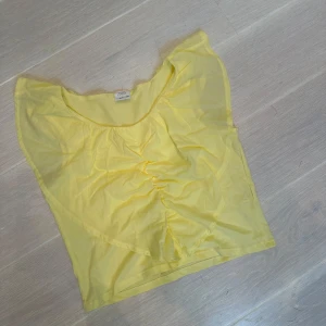 Gul ärmlös topp från Zara - Snygg gul ärmlös topp från Zara med volangdetalj vid axlarna och lätt rynkning framtill. 