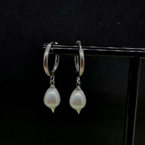 Silvriga örhängen med vita pärlor - Stilrena silvriga hoops med droppformade vita pärlor som hänger ned. Perfekta för dig som gillar en klassisk men ändå trendig look. Passar till både enkla och mer uppklädda outfits.