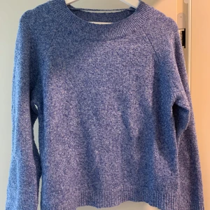 Blå stickad tröja från Vero Moda - Mysig blå stickad tröja från Vero Moda i storlek S. Tröjan har en rund halsringning, långa ärmar och ribbade muddar vid ärmslut och nederkant. Perfekt för lager-på-lager och chill dagar. Enkel och stilren design som funkar till det mesta.