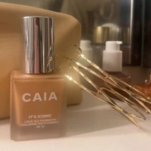 CAIA It's Iconic Liquid Silk Foundation 3W - Flytande foundation från CAIA i nyansen 3W. Kommer i en fyrkantig glasflaska med silvrigt lock och applikator. Innehåller hyaluronsyra och vitamin C, SPF 20. Aldrig använd! 