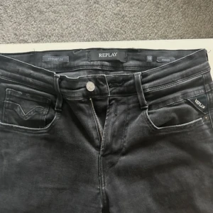 Svarta Replay Hyperflex Anbass jeans - Säljer ett par svarta Replay Hyperflex Anbass jeans i storlek W30. Jeansen har klassisk femficksdesign, dragkedja och knapp framtill samt diskreta Replay-detaljer på fickorna. Stretchigt material för extra komfort.