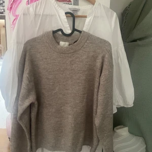 Beige stickad tröja från H&M - Mysig beige stickad tröja från H&M i storlek XS. Tröjan har rund halsringning och långa ärmar, perfekt för lager-på-lager eller att bära som den är. Enkel och stilren design som passar till mycket.