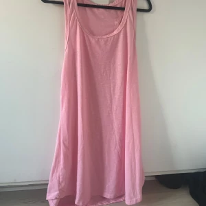 Rosa ärmlös klänning - Säljer en enkel och luftig rosa klänning med rund halsringning. Klänningen är ärmlös och har en avslappnad passform, perfekt för varma dagar. Tillverkad i mjukt material som känns skönt mot huden. 