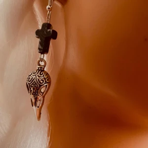 By prisförslag- 1 st Örhänge med svart kors och dekorerad dödskalle - Unikt örhänge med ett svart kors i plast och en detaljerad dödskalle i metall med snirkliga mönster. Perfekt accessoar för dig som gillar alternativ stil och vill sticka ut.