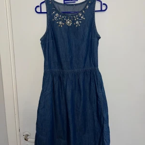 Jeansklänning med kristallstenar - En snygg och somrig ärmlös jeansklänning från FOREVER 21  med rund halsringning och glittriga strassdekor framtill. Kan bäras med ett brunt skinn bälte! 💙