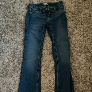 Blå bootcut jeans med broderade detaljer - Säljer ett par blå bootcut jeans med snygga broderade detaljer på bakfickan.