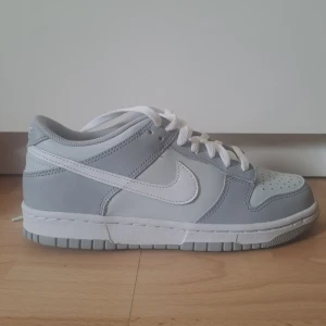 Nike Dunk Low i grått och vitt - Säljer ett par Nike Dunk Low i stilren grå och vit färg. Skorna har klassisk låg siluett, vit sula och vita skosnören. Skriv om du vill ha fler bilder eller andra frågor!                    