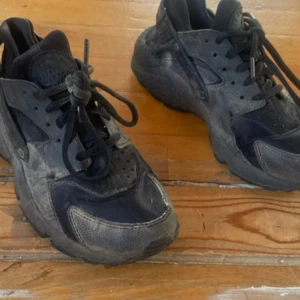 Svarta Nike sneakers - Säljer ett par svarta Nike sneakers med robust sula och snörning. Skorna har en sportig design med paneler i olika material och rund tå. Perfekta för dig som gillar streetwear och vill ha en klassisk look.