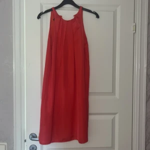 Röd/ korall klänning från Mango - Säljer en röd/ korall klänning från Mango. Klänningen har en rund halsringning och knäppning i nacken. Storlek xs. 