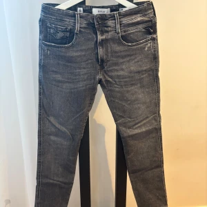 Replay Anbass svarta jeans - Säljer ett par Replay Anbass jeans i svart tvätt med klassisk femficksdesign. Jeansen har normal passform och är tillverkade i ekologisk bomull. Perfekta för dig som gillar stilrena och bekväma jeans med snygg faded effekt.