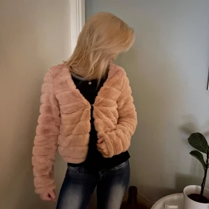 Ljusrosa teddyjacka - Mysig ljusrosa teddyjacka med lång ärm och dragkedja framtill. Jackan har en fluffig och mjuk struktur som ger en trendig look. Perfekt för att hålla värmen under kyliga dagar. Passar dig som gillar en lite oversized stil.