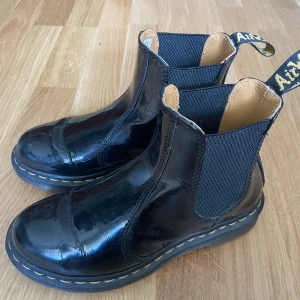 Svarta Dr. Martens chelsea boots - Säljer ett par klassiska svarta Dr. Martens chelsea boots i lackat skinn. De är creasade men inget som stör särskilt mkt enligt mig. Är i storlek 37 och ganska så tighta. Lite för tight passform för mig tyvärr. 
