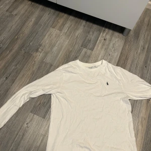 Vit långärmad tröja från Ralph Lauren - Säljer en klassisk vit långärmad tröja från Ralph Lauren med den ikoniska broderade loggan på bröstet. Perfekt basic-plagg med rund hals och mjukt bomullsmaterial.
