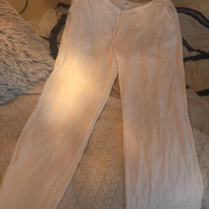 Vita linnebyxor med dragsko - Säljer ett par luftiga lågmidjade  vita linnebyxor med dragsko i midjan. Perfekta för varma dagar och har en avslappnad passform. Byxorna är raka i modellen och har en enkel, stilren look. Är från HM men har klippt bort lappen 