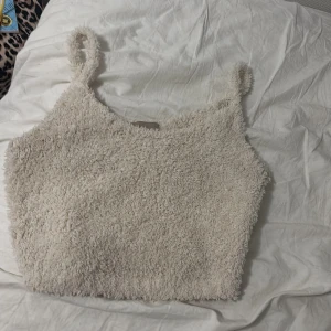 Beige fluffig linnetopp - Supermjuk och fluffig beige linnetopp med breda axelband. Perfekt för att skapa en mysig och trendig look. Toppen är ärmlös och har en croppad passform som passar till många olika outfits.