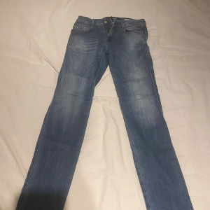 Blå Replay Anbass jeans - Säljer ett par klassiska blå jeans från Replay, modell Anbass. Jeansen har skinny passform och raka ben, med fem fickor och dragkedja. Perfekta för dig som gillar stilrena och tidlösa jeans. Buda gärna! FÖRST TILL KVARN! 
