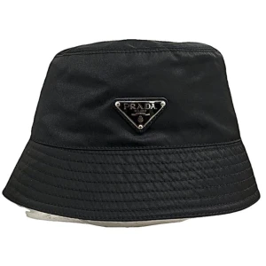 Svart bucket hat från Prada - Stilren svart bucket hat från Prada. med klassisk logga framtill. Hatten har en enkel design med bredare brätte och passar perfekt till sommaren.