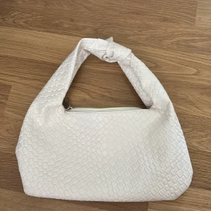 Vit axelväska med knut och ormmönster - Säljer en snygg vit axelväska med ormmönstrad struktur och en cool knut på axelbandet. Väskan har dragkedja upptill och är perfekt för att lyfta din outfit. Superenkel att matcha och rymmer det viktigaste! Köpt på vinted så vet ej märke, inga defekter, säljer för den tyvärr inte kom till användning