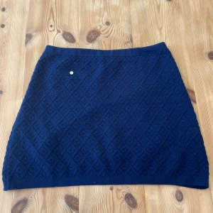 Mörkblå stickad kjol från Massimo Dutti - Säljer min sååå fina stickade mörkblå kjol från Massimo Dutti. Den har ett jättefint mönster och en liten ficka på framsidan uppe i hörnet med en guldig knappdetajl. Den är kort och rak i passformen. Materialet är väldigt mjukt och stickat. Så stilrent plagg med en extra touch!! 🌸