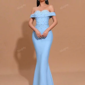 Ljusblå långklänning med pärlor - Elegant ljusblå långklänning med offshoulder och figurnära passform. Klänningen har pärldetaljer över byst och överdel, samt en lätt utsvängd kjol. Perfekt för bal eller fest. Dragkedja i ryggen och vacker axelbandslös design.