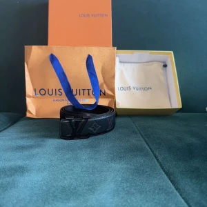 Bälte med spänne L och V - Ett helt nytt bälte med skärpet där det står bokstäverna L och V och följer med kvitto förpackning. Helt ny lite skadad förpackning