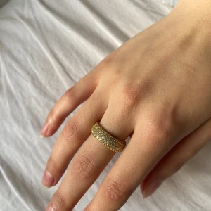 Guldfärgad ring med stenar från Pandora - Säljer en snygg guldfärgad ring från Pandora, täckt med glittrande stenar runt hela ringen. Perfekt för dig som vill ha något som sticker ut och glittrar lite extra. Fick den av mitt ex för några dagar sen, gjorde slut idag. Vill sälja alla presenter jag har fått av honom. Inte fast pris