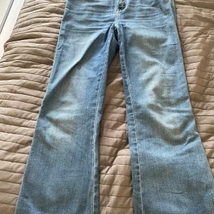 Blå jeansbyxor från lager 157 - Klassiska blåa utsvänga jeansbyxor från lager 157 med utsvängda ben och normal passform. Byxorna har två bakfickor med knappdetaljer och synliga sömmar i kontrastfärg. Perfekta för en avslappnad stil.