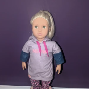 Ljuslila hoodie med texten MEOW - Säljer en our Generation docka i fint skick med ett sätt kläder som är till köpt men igår i priset hör av er vid funderingar ❤️ (nypris är ungefär 500 kr)