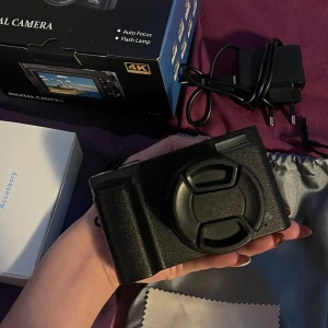 Digital kamera 4K med tillbehör - Säljer en svart digital kamera med 4K-upplösning. Kameran har autofokus, blixt och digital zoom. Medföljer laddare, USB-kabel, handledsrem, putsduk och originalkartong. Perfekt för dig som vill ta snygga bilder och filmer.