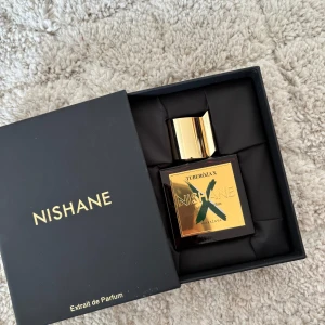 Nishane Tuberóza X Extrait de Parfum 50 ml - Lyxig parfym från Nishane i doften Tuberóza X. Flaskan är fyrkantig i mörkrött glas med guldfärgat lock och guldig etikett med grönt X. Extrait de Parfum, 50 ml. Kommer i elegant svart ask med gulddetaljer. Hör gärna av er vid frågor och pris kan absolut diskuteras!
