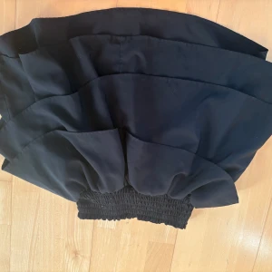 Svart volangkjol från H&M - Säljer en svart kort volangkjol från H&M med bred resår i midjan. Kjolen är i storlek 145/152, men passar som XS-S! Kjolen har flera lager tyg som ger en snygg volangeffekt och en luftig känsla. Perfekt att styla med en enkel topp eller stickad tröja. ALLTID 10% RABATT NÄR DU KÖPER 2 PLAGG ELLER FLER💗🫶!!!