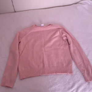 Ljusrosa stickad tröja - Mysig ljusrosa stickad tröja med rund halsringning och ribbade muddar vid ärmslut och nederkant. Perfekt för lager-på-lager och enkel att matcha med jeans eller kjol. Kvaliteten på tröjan är väldigt bra! 