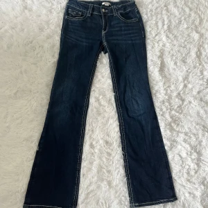 Mörkblå bootcut jeans  - Skitsnygg jeans frän Gina Tricot . Midjan är lăg och gylfen bestär av knapp och dragkedja. Midjan är justerbar pả insidan sả att jeansen ska sitta sà bra och bekvämt som möjligt. Benen är avslappnade upptill och utsvängda nedtill. Bakfickorna har lock och knapp. Använd endast 1 gảng. Jag r 172 sả längden är perfekt.