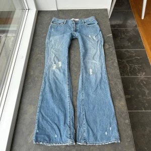 Jeans bootuct y2k - Så himla coola jeans med slitningar och snygga fickor bak! Tyvärr finns ingen bild på då de inte passar mig. Midjemått: ca 40-41 cm.  innerbenslängd: ca 80 cm.  midjehöjd: ca 21 cm . Svårt att uppskatta en exakt storlek men kolla på måtten. 