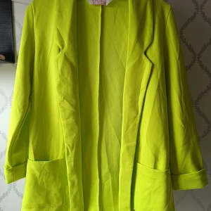 Neongul kavaj  - Säljer en neon gul/grön kavaj från Amisu/New Yorkeri istorlek XS/34. Kavajen har långa ärmar, två stora fickor framtill och öppen front utan knäppning. Perfekt för dig som vill sticka ut med en färgstark look. Använd endast 1 gång!!! 50 kronor men priset kan diskuteras 