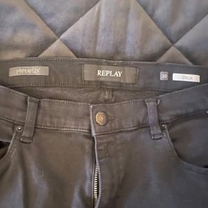 Svarta Replay Hyperflex jeans - Svarta jeans från Replay Hyperflex-serien med klassisk femficksdesign och dragkedjegylf. Modellen heter Stella och har en smal passform som sitter snyggt längs benen. Perfekta för dig som vill ha stretchiga och bekväma jeans i stilren look.