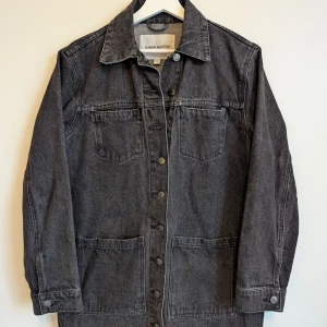 Carin Wester - "Tori" Lång svart jeansjacka 36 - Sparsamt använd svart jeansjacka från Carin Wester med klassisk krage, knappar framtill och stora fickor. Jackan har längre passform som går ner till mitten på låret (på mig som är 160cm lång). Från rökfritt och djurfritt hem.