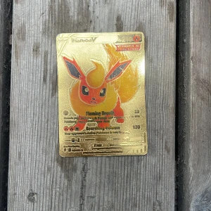 Flareon V Pokémonkort i guld - Säljer ett exklusivt Flareon V Pokémonkort i guldutförande. Kortet har en glansig, metallisk yta med motiv av Flareon och text i svart och rött. Baksidan har Pokémon-loggan i guld. Perfekt för samlare! Några få repor men det kan man nog fixa med sandpapper!Man får Järna ge prisförslag och ge frågor☺️