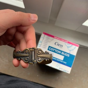 Antikt ormarmband i bronsfärg - Säljer ett unikt armband i bronsfärg med två ormar som möts framtill. Armbandet har vackra ingraverade detaljer och en antik känsla. Perfekt för dig som gillar smycken med karaktär och mytologiska inslag.