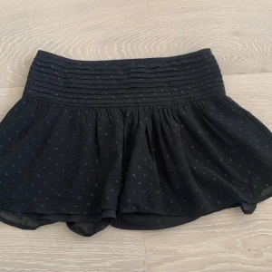 Svart glittrig kjol från Gina Tricot - Superfin, lågmidjad kjol från ginatricot med paljetter i storlek 146/152 och xxs. Den är i mycket bra skick och har inga defekter.