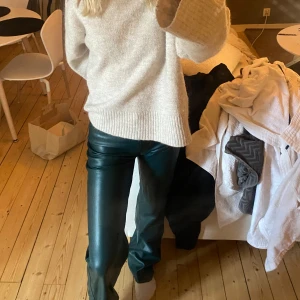 Gröna skinnbyxor med normal passform - Snygga gröna skinnbyxor med normal passform och hög midja. Byxorna har utsvängda ben och en stilren look som passar till många olika outfits. Perfekta för dig som vill ha ett trendigt och edgy plagg i garderoben.